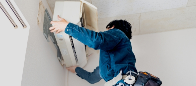 男性がエアコンを取り外している