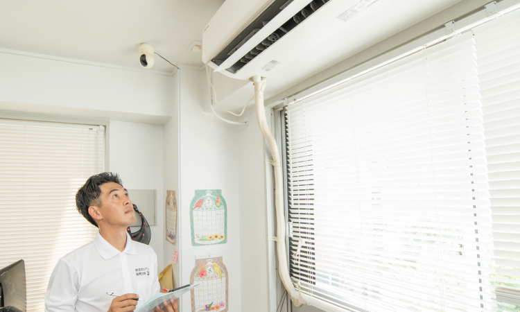 男性が室内機を確認してメモをとる様子