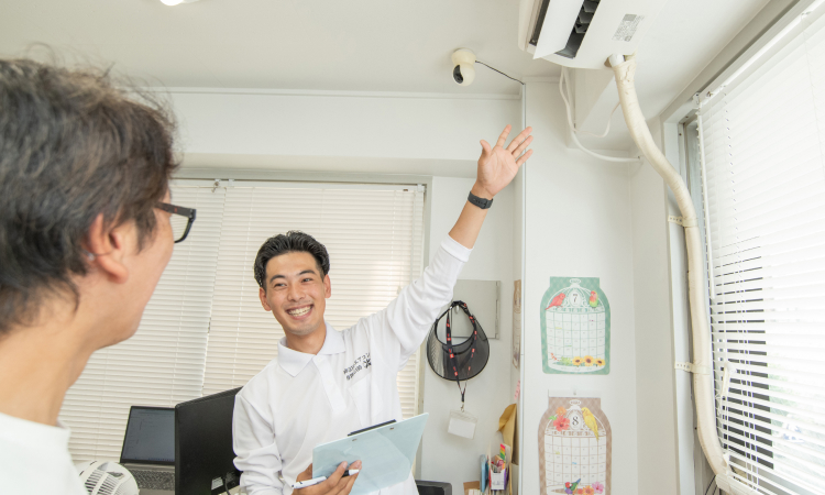 男性が笑顔でお客様に室内機の説明を行なっている