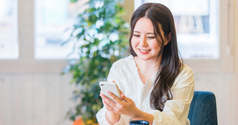 女性が笑顔で携帯を触っている