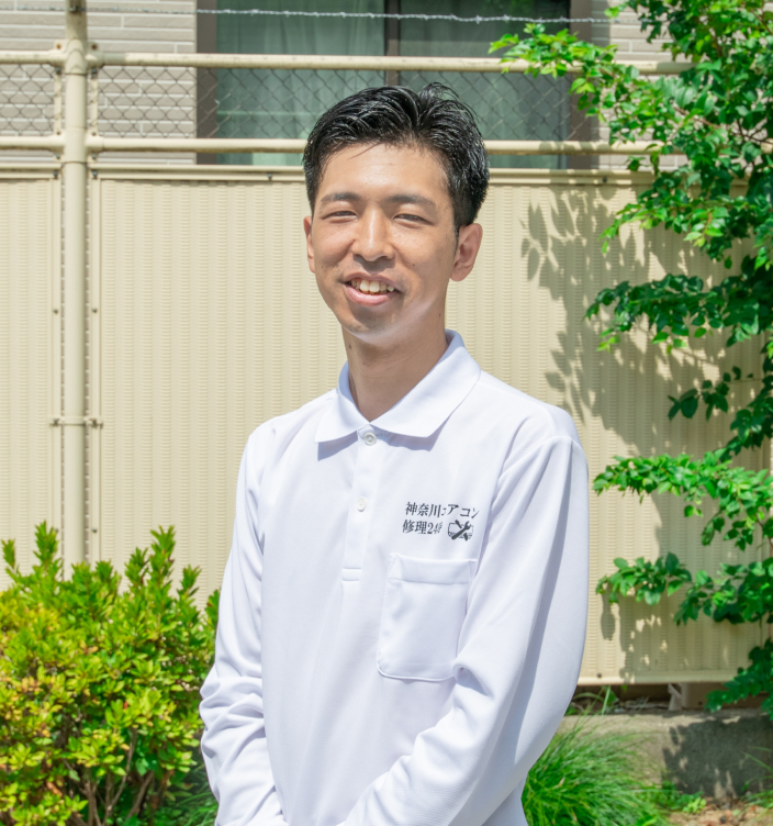 木の前で写真を撮っている、神奈川エアコン修理24時の代表